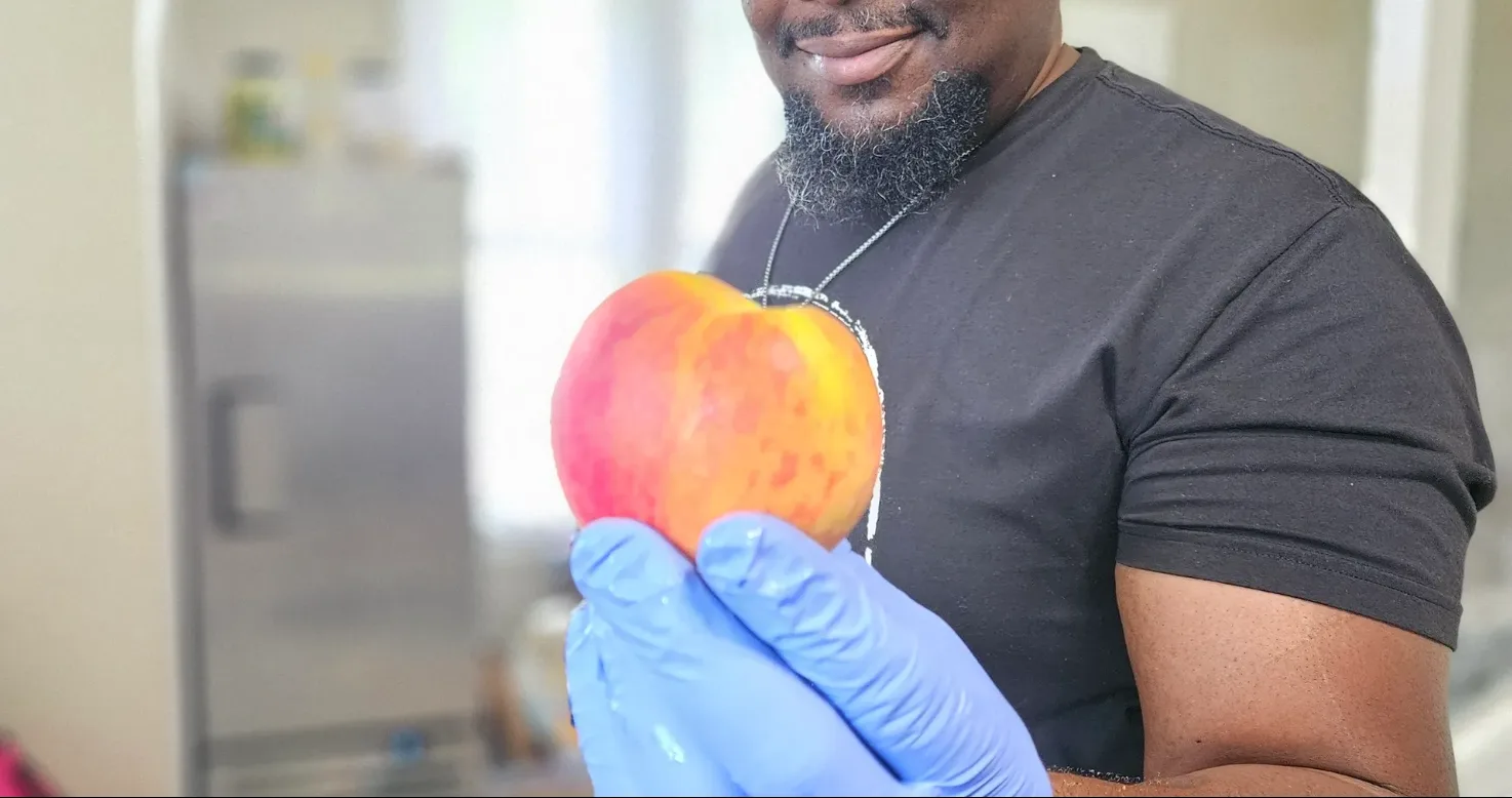 Chef B holding a fresh peach in his prep kitchen in Swansea, IL