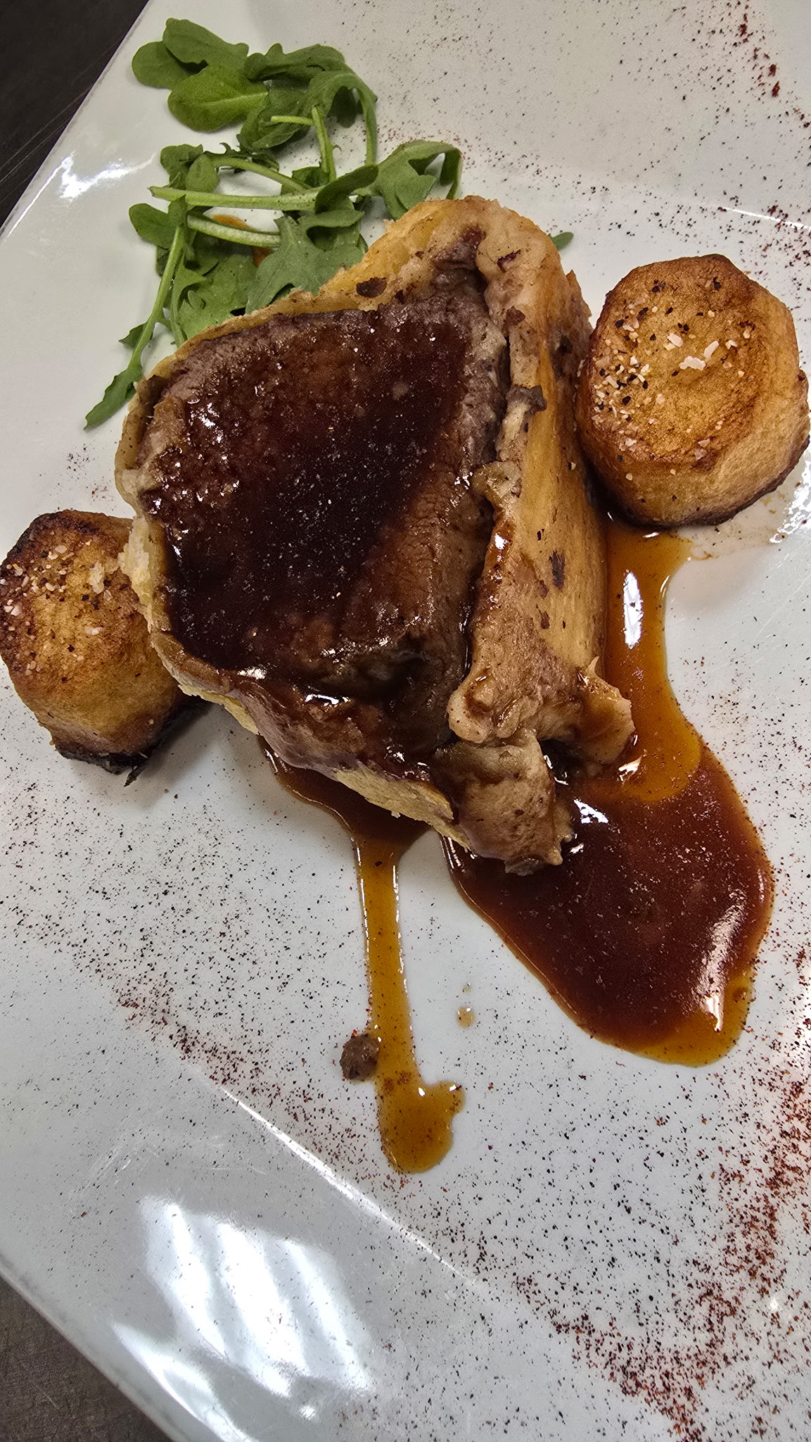 Beef Wellington sliced tableside with red wine demi-glace and crisped fondant potatoes