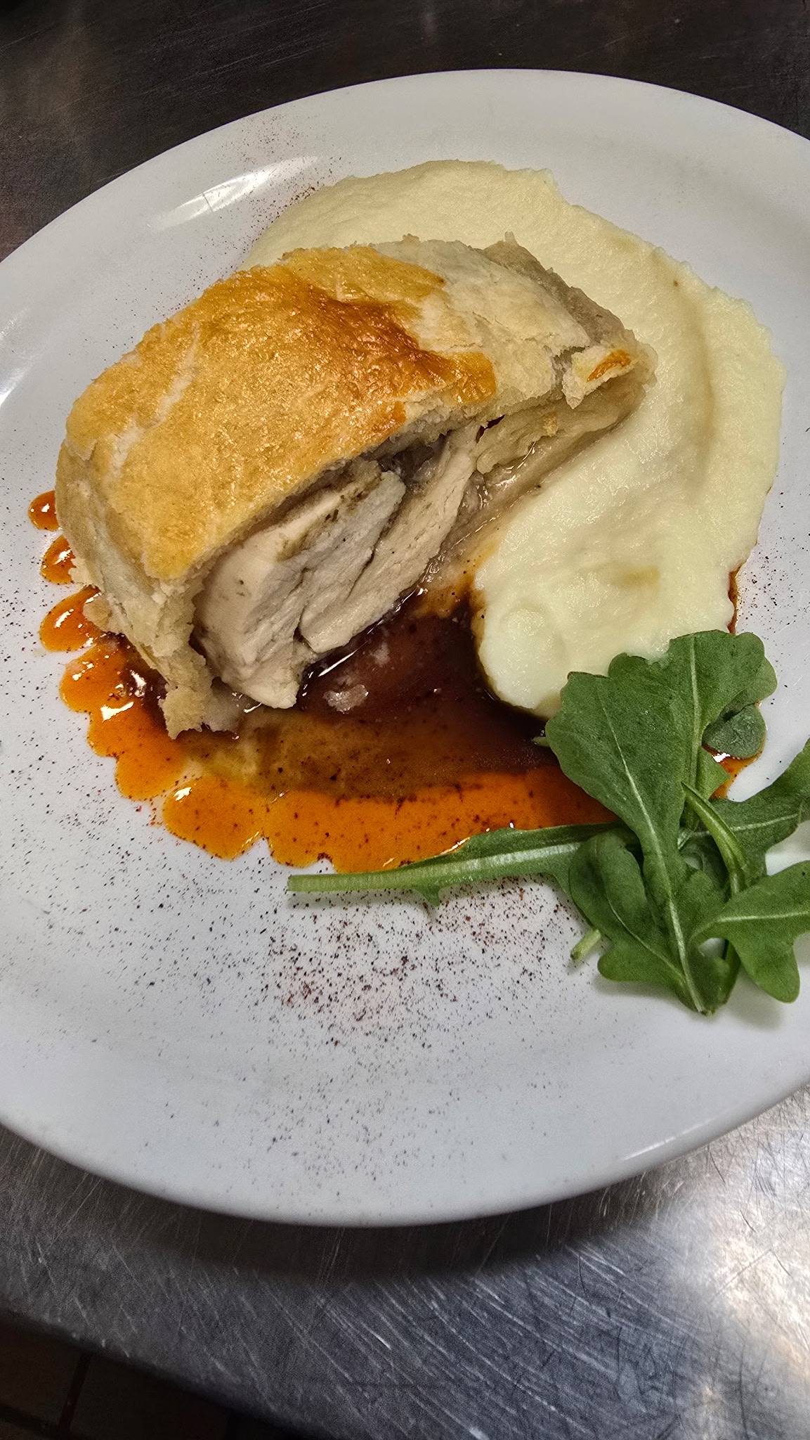 Chicken Wellington in golden puff pastry, sliced over pureed parsnips with a red wine demi-glace