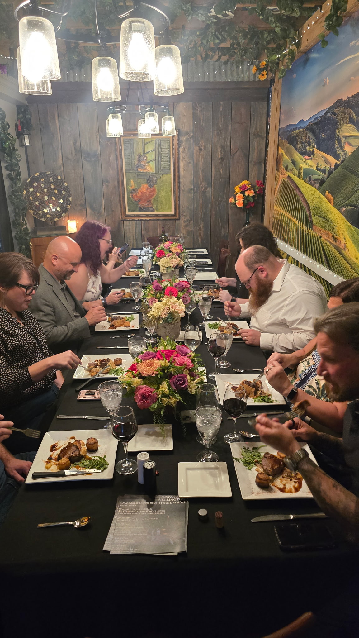 Guests seated at a private five-course tasting dinner, dining beneath string lights at a Chef B pop-up event