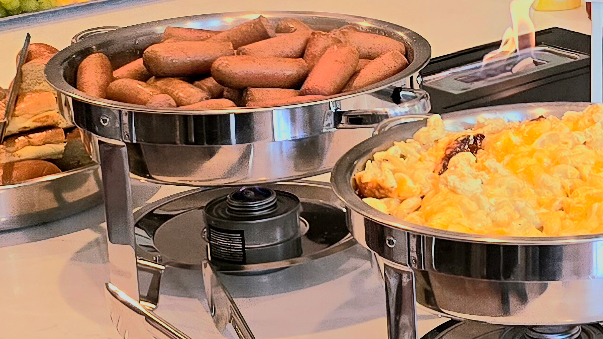 Chafing dishes of all-beef hot dogs and Grandma's baked mac and cheese ready to serve at a catered event